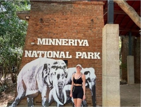 A guest standing at the Minneriya National Park entrance sign before a safari